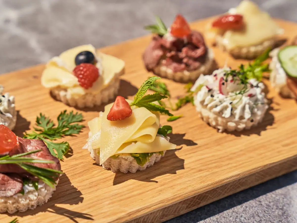 Ein Holzbrett mit kunstvoll angerichteten Canapés auf einem Tisch.