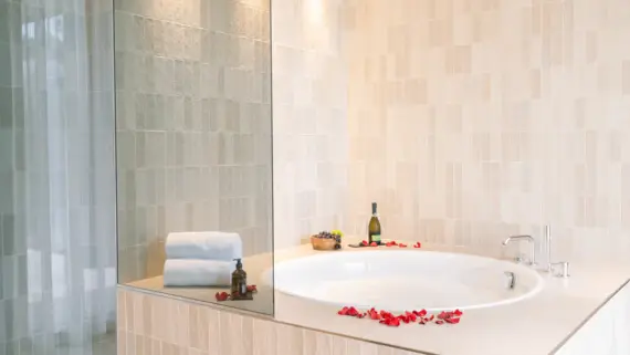 Bathtub with rose petals on the rim in an elegantly designed bathroom.