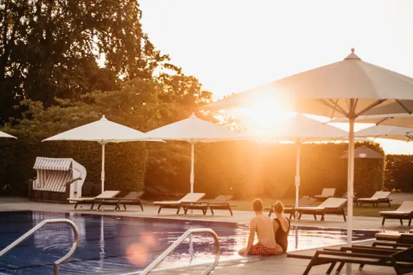 Ein Paar sitzt am Pool im Freien.