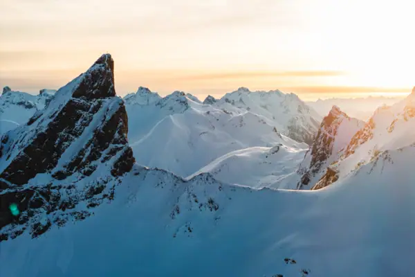 Schneebedeckte Berggipfel mit untergehender Sonne im Hintergrund