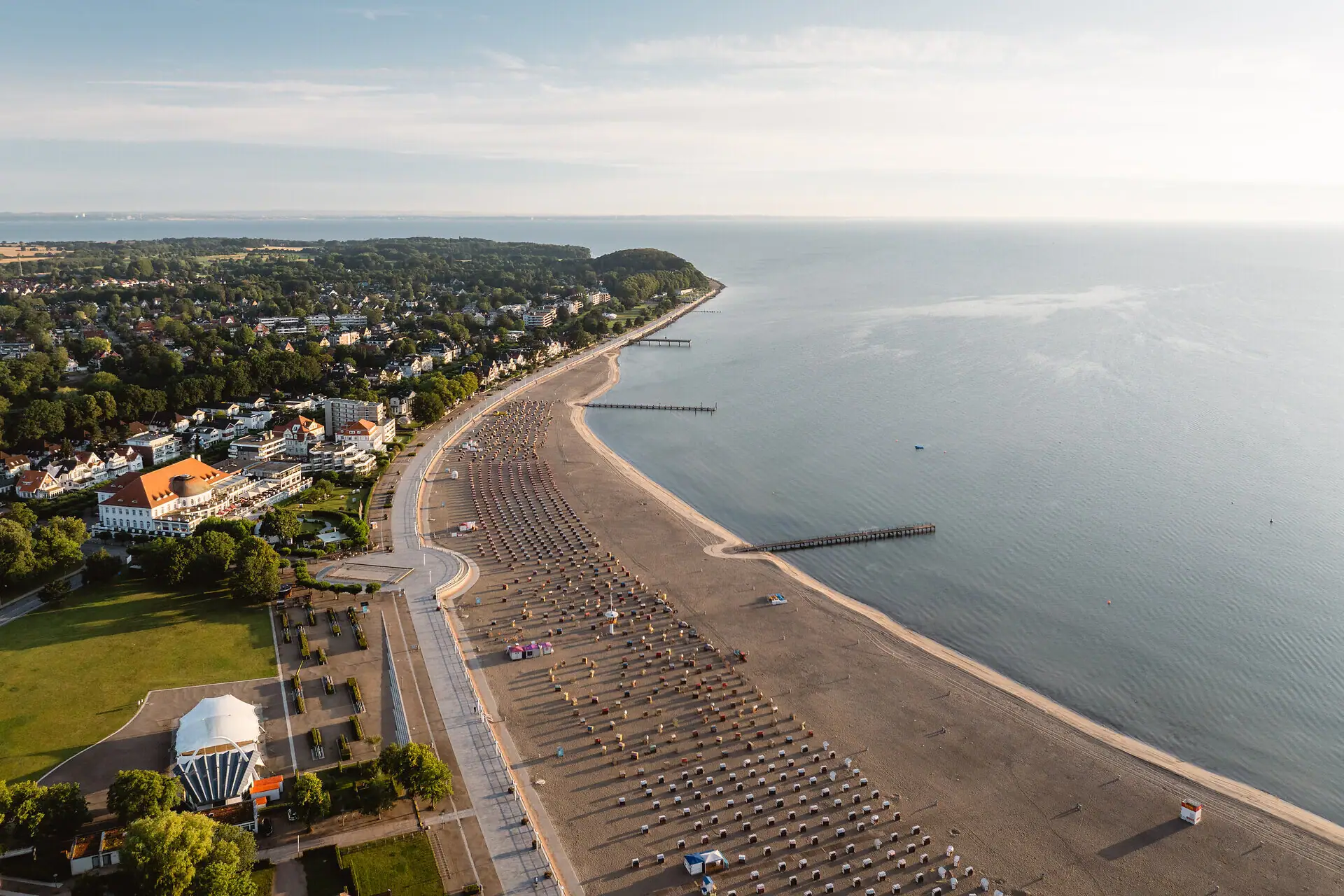 Strand mit zahlreichen Sonnenschirmen und Gebäuden am Wasser.