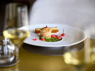 Teller mit Essen auf einem Tisch, umgeben von Weingläsern und Besteck.