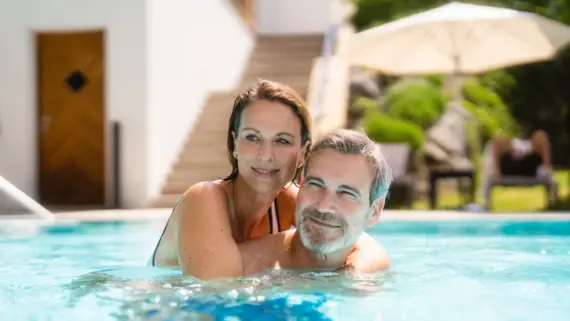 Ein Mann und eine Frau lächeln und haben Spaß im Swimmingpool.