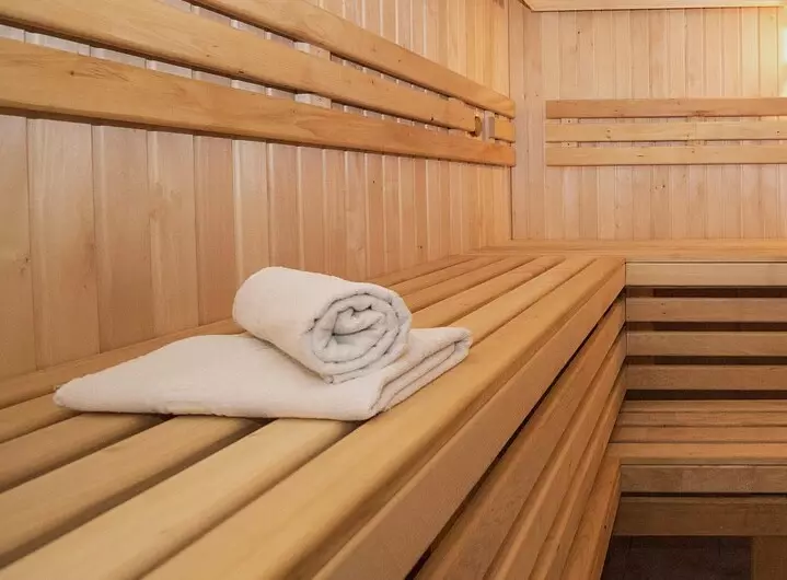 Eine Saunabank auf dem zwei gefaltete weiße Handtücher liegen.
