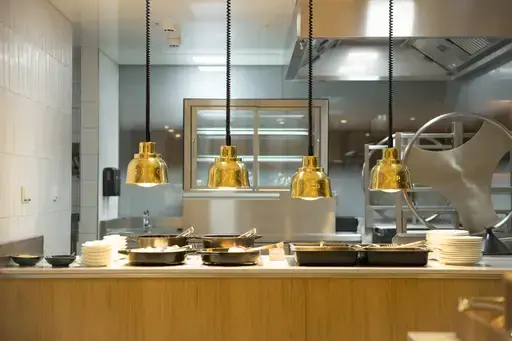 FREYHEIT Grill & Bar Küche mit hängenden Pfannen an der Decke und sichtbarem Waschbecken.