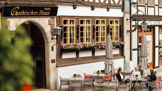 Außenansicht des Hotels Gotisches Haus in Wernigerode mit historischer Fachwerkfassade und blumengeschmückten Fenstern.
