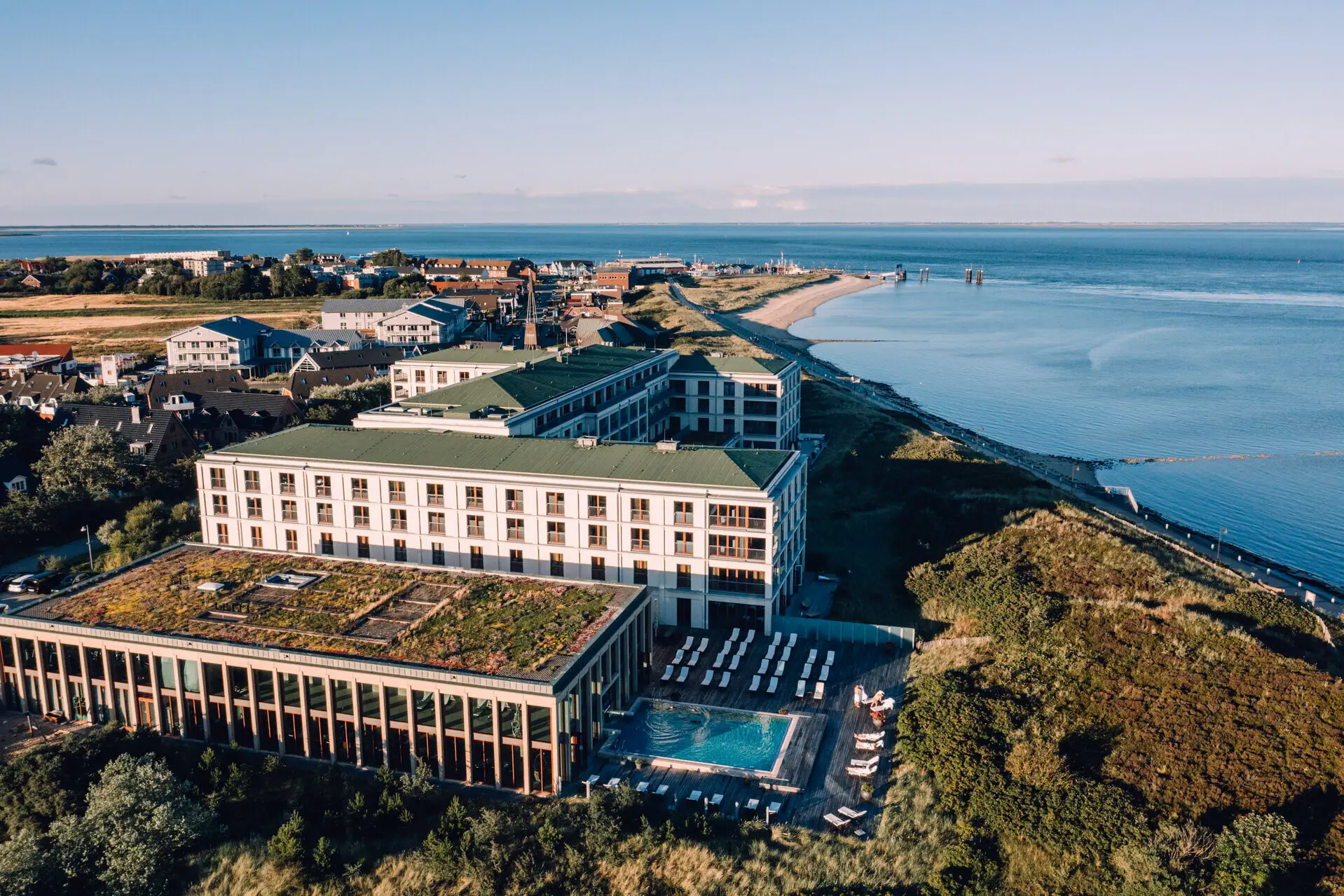 A-ROSA Sylt Das A-ROSA Hotel Sylt mit einem Pool und dem Strand mit der Nordsee im Hintergrund