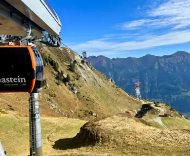 Gondel der Schlossalmbahn in Gastein mit Blick auf die herbstlich gefärbte Berglandschaft und das Gasteiner Tal bei klarem Himmel.
