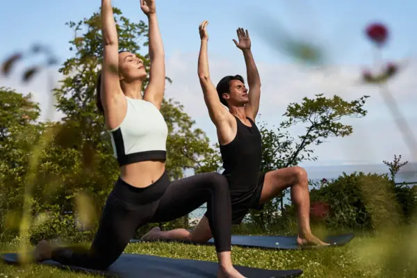 Ein Mann und eine Frau machen draußen Yoga.