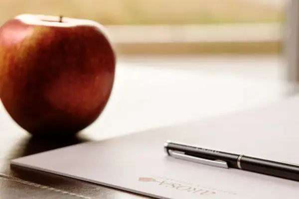 Ein Stift auf einem Blatt Papier neben einem Apfel.