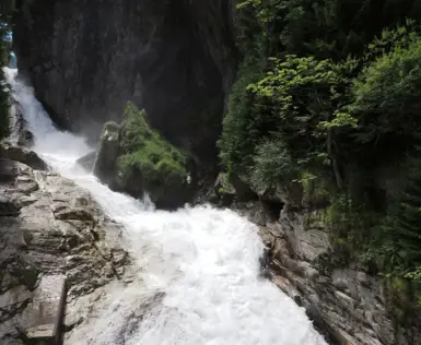 Eindrucksvoller Blick auf den tosenden Gasteiner Wasserfall, umgeben von steilen Felswänden und dichter, grüner Vegetation im Herzen von Bad Gastein.