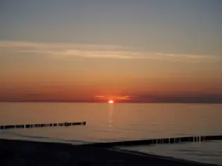 Sonnenuntergang über einem ruhigen Gewässer bei Abenddämmerung.