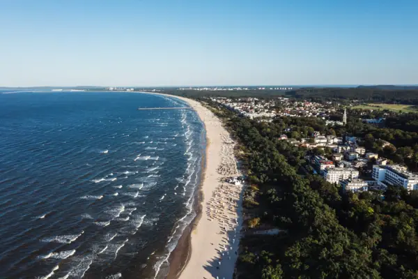 Strand mit Bäumen und Gebäuden am Ufer.
