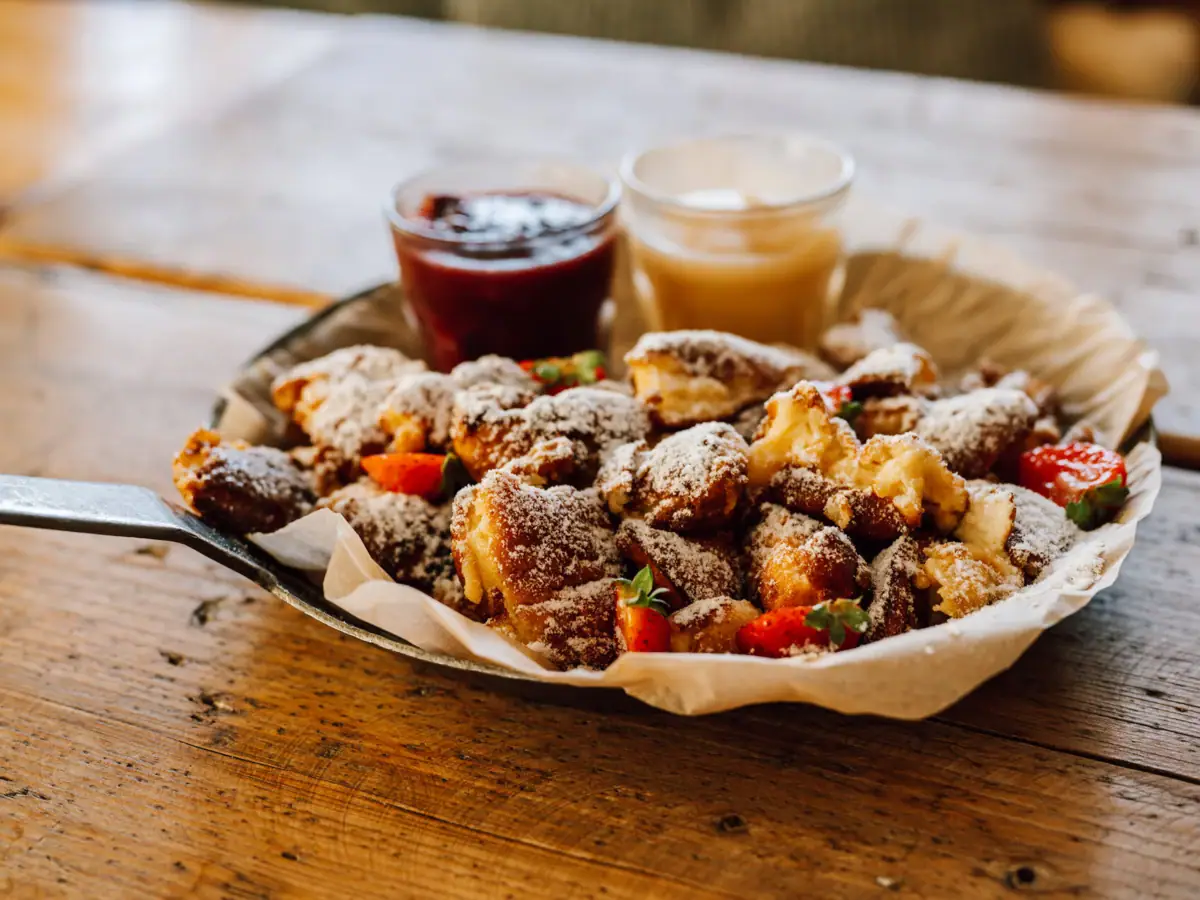 Kaiserschmarrn Ein Teller mit Essen und zwei Gläsern Marmelade.