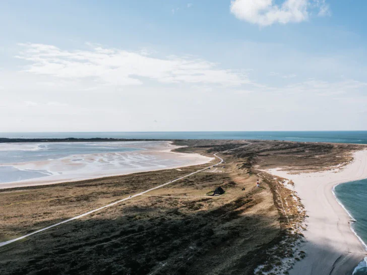 Spiaggia con sabbia e acqua, circondata da un paesaggio costiero.