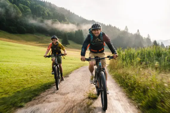 Zwei Personen fahren auf einem Feldweg Fahrrad.