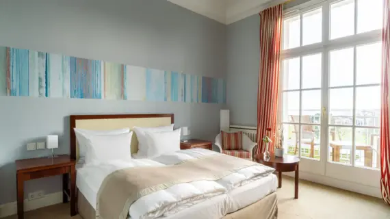 Ein Hotelzimmer mit einem großen Bett und großen Fenstern mit Zugang zu einem Balkon.