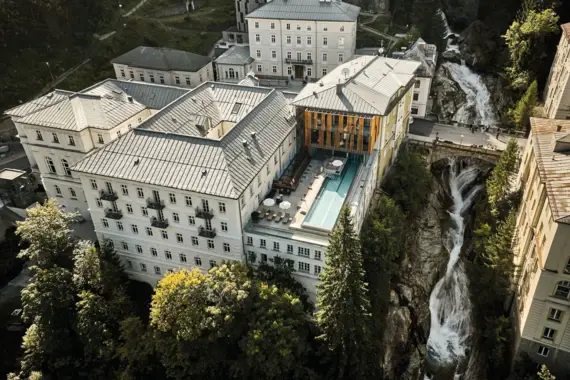 Ein Gebäude mit einem Pool und einem Wasserfall im Freien, umgeben von Bäumen.