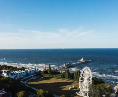 Großes Gewässer mit Riesenrad und Pier im Vordergrund.