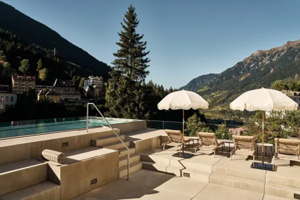Ein Pool mit Sonnenschirmen und Liegestühlen an einem sonnigen Tag.