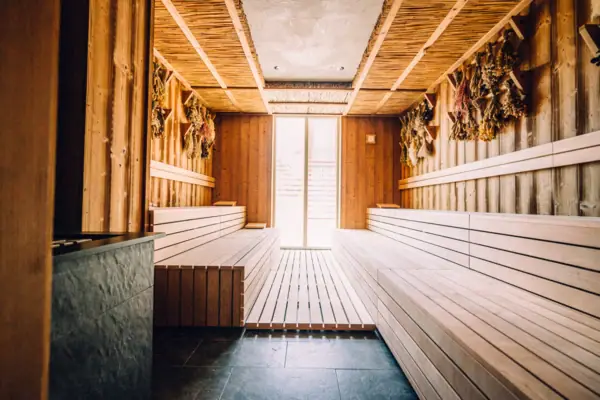 Ein Innenraum einer Sauna mit Holzbänken und einer Tür.