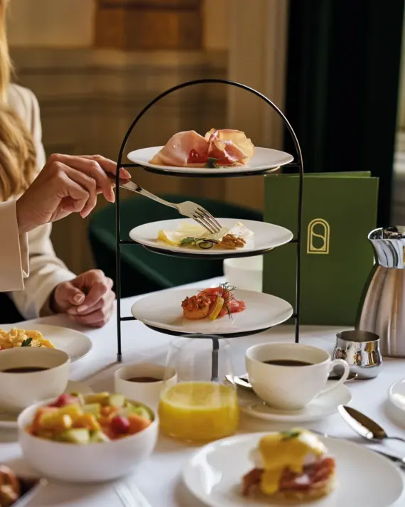 Elegant gedeckter Frühstückstisch im Straubinger Grand Hotel mit dreistöckiger Etagere, frischem Obstsalat, Kaffee, Orangensaft und liebevoll angerichteten Köstlichkeiten.