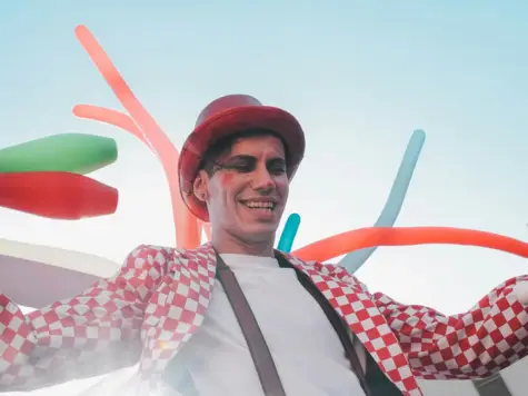 Ein Clown auf Stelzen mit Luftballons im Hintergrund.