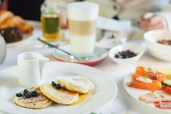 Frühstück Ein Teller mit Pfannkuchen, garniert mit Heidelbeeren und Puderzucker.