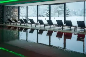 Ein Pool mit Stühlen vor einem großen Fenster.