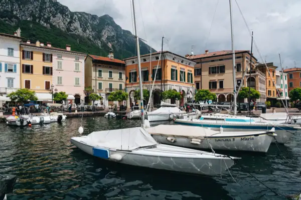 Boote im Hafen mit Gebäuden und Bergen im Hintergrund am Gardasee.