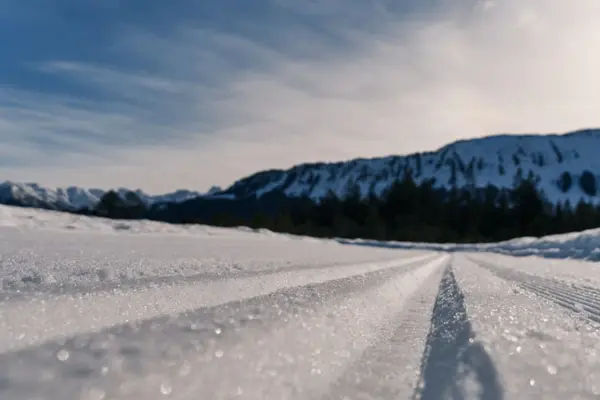 Schneebedeckter Boden mit Skispuren in einer winterlichen Landschaft.