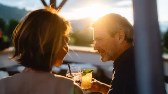 Ein Mann und eine Frau stoßen mit Cocktails auf einer Terrasse an
