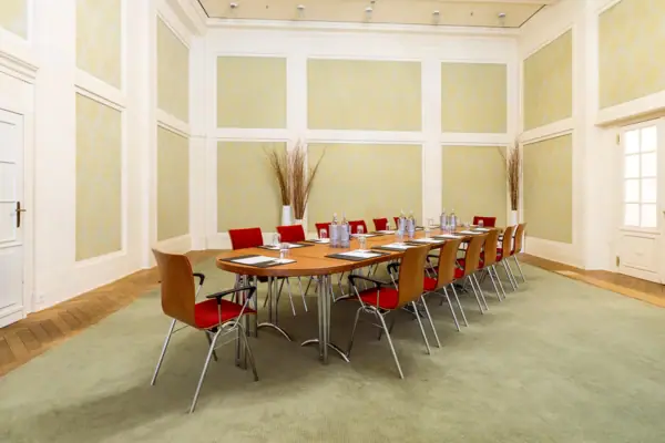 A-ROSA Veranstaltungsraum Grüner Saal Ein Zimmer im A-ROSA Travemünde mit einem Tisch und Stühlen.