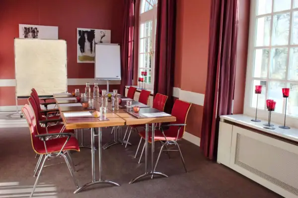 Ein roter Veranstaltungsraum mit einem Tisch und Stühlen.