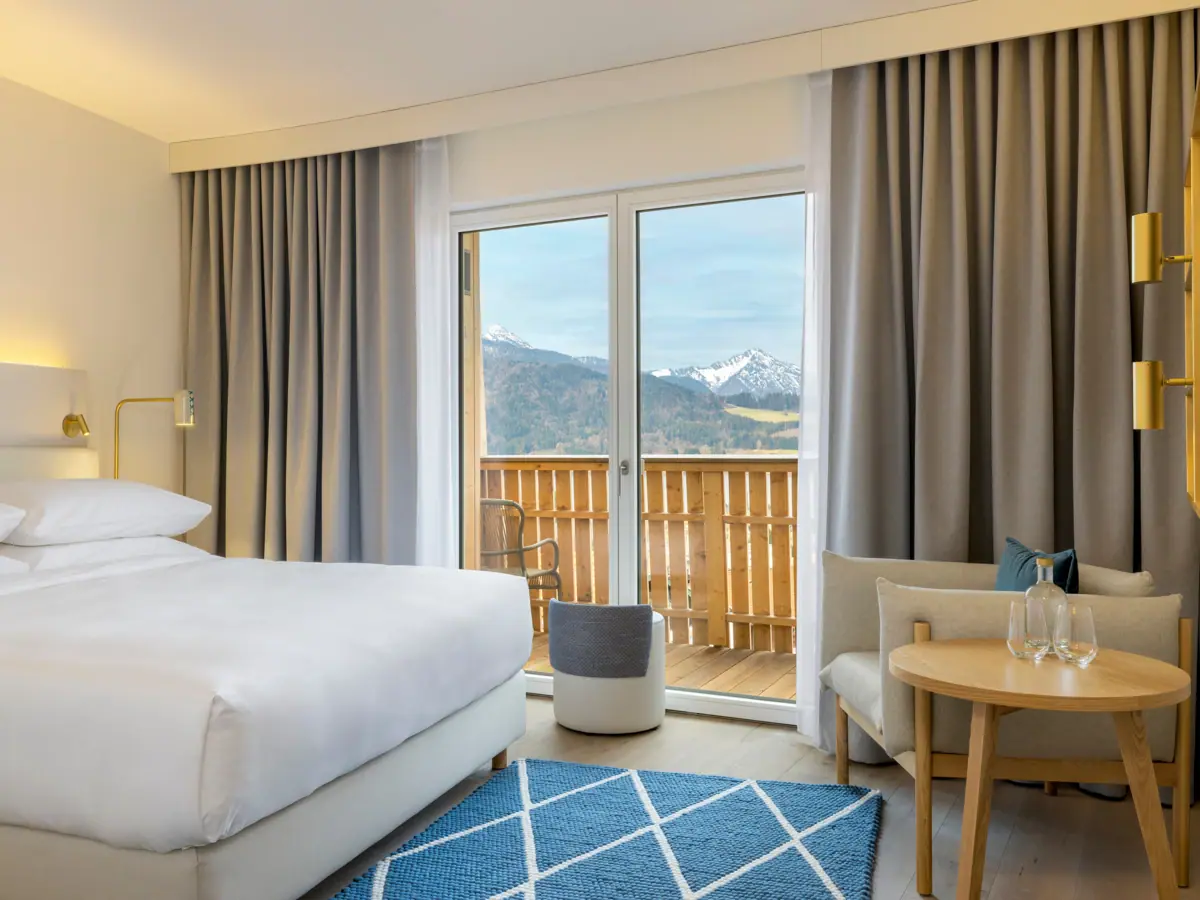 Hotelzimmer mit Bett, Teppich und Sessel.