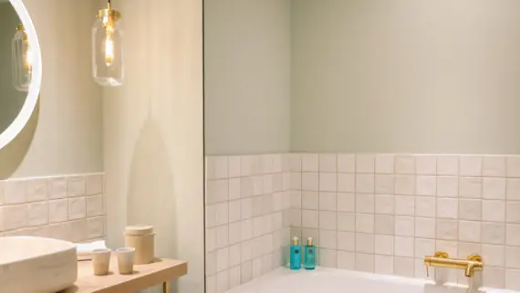 Bathroom featuring a bathtub and a sink, complemented by tiled walls and modern fixtures.