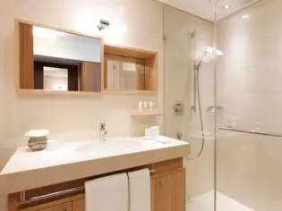 Ein Badezimmer mit einem Waschbecken und einer verglasten Duschkabine.