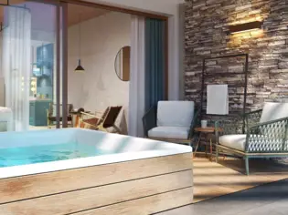 Luxurious spa suite with a large, rectangular wooden whirlpool in the foreground, filled with blue water that invites you to relax. Large window fronts provide a seamless transition to the sleeping area, where a cozy bed overlooks the pool. To the right of the suite is a stylish sitting area with two modern armchairs next to a wall of natural stone, creating a calming atmosphere. The suite combines modern comfort with natural elements.