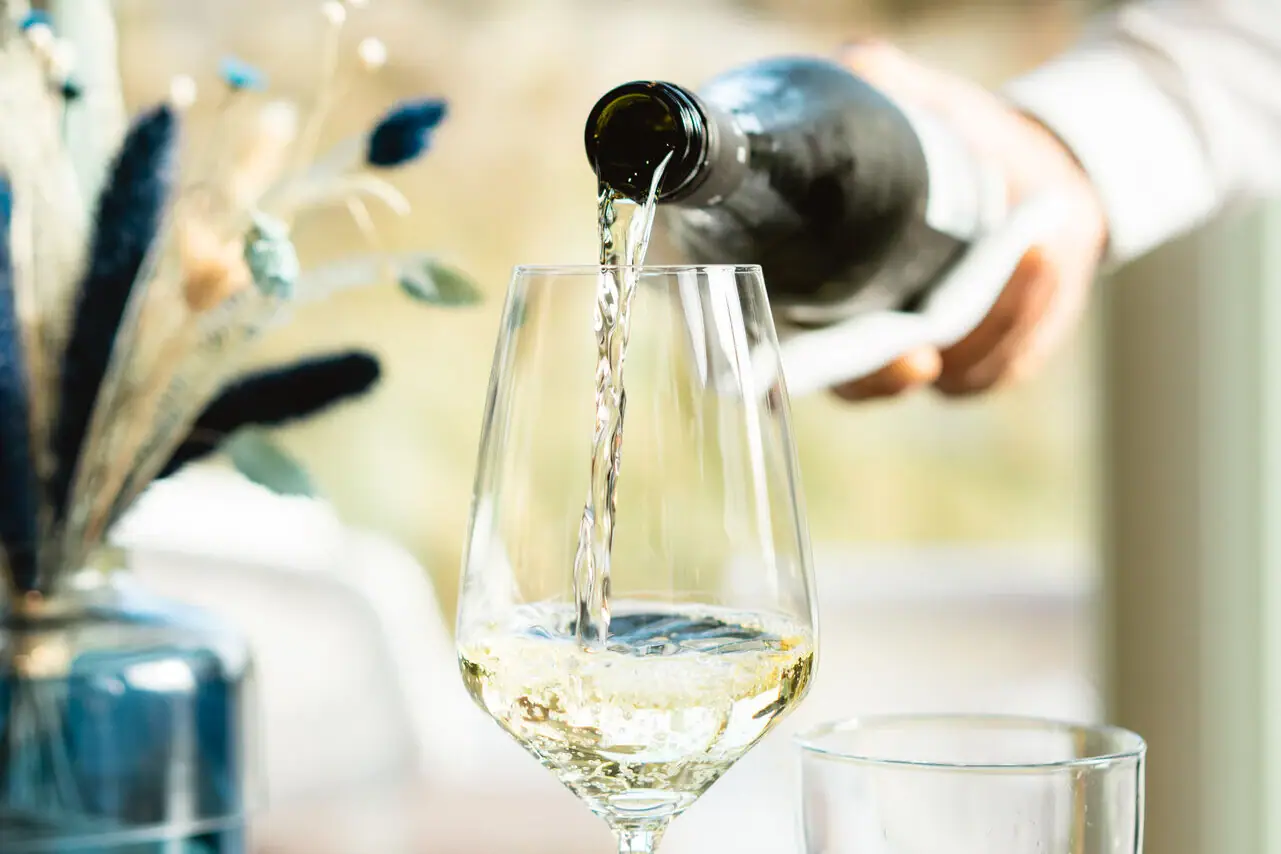 Weinservice Eine Person gießt Wein in ein Glas.