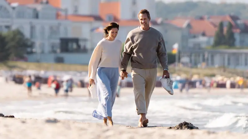 Ein Mann und eine Frau spazieren am Strand.