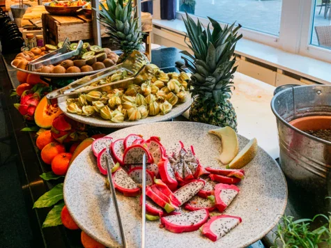 Tavolo buffet con assortimento di frutta e verdura, decorato con elementi floreali.