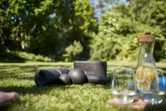 Yogamatten und ein Glas Wasser auf Gras.