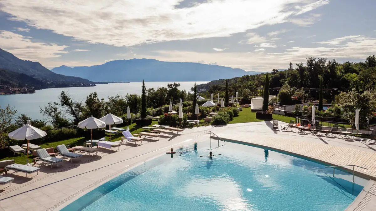 Ein Pool mit Liegestühlen und Sonnenschirmen am Wasser.