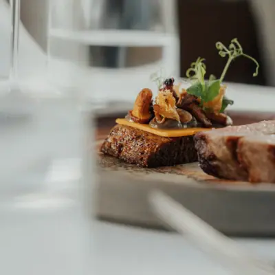 Ein Teller mit Essen auf einem Tisch mit Weinglas.