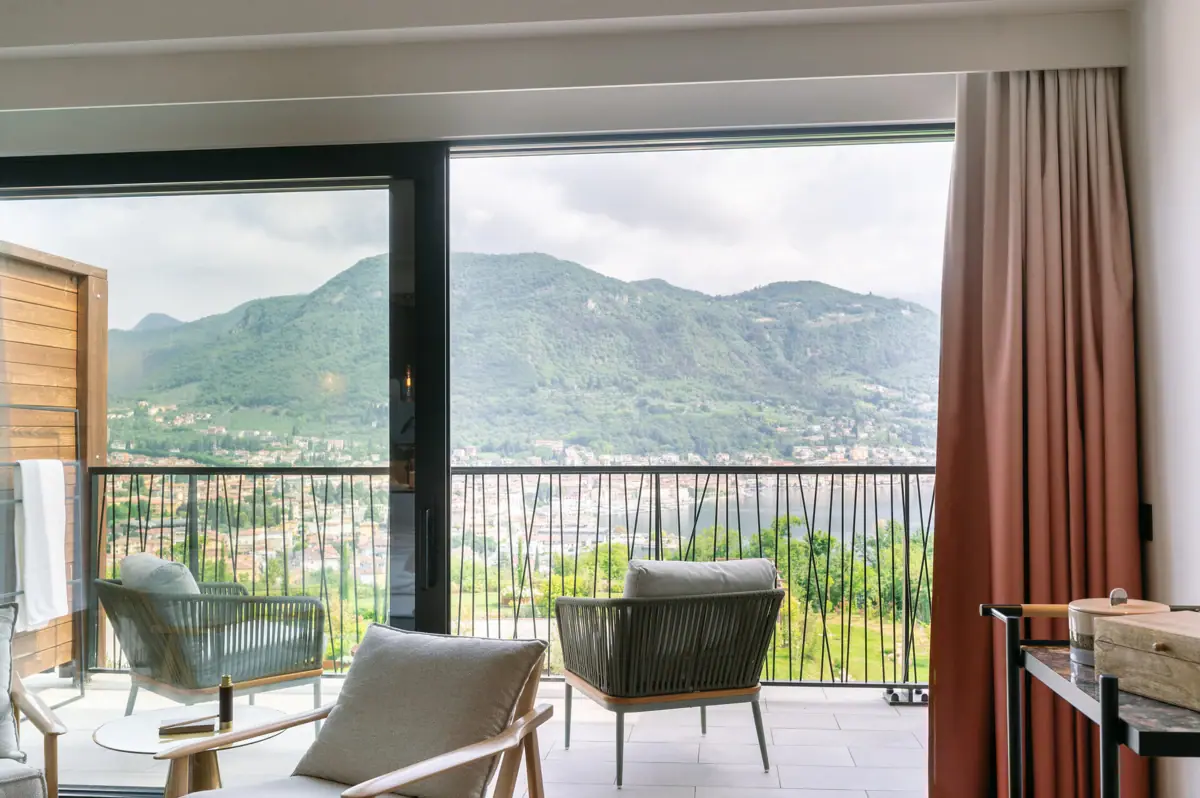 Ein Zimmer mit Balkon und Blick auf Berge und Bäume.