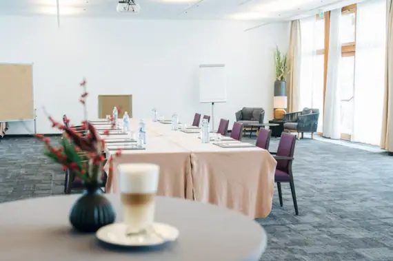 Ein Konferenztisch mit Stühlen und einem Getränk darauf.