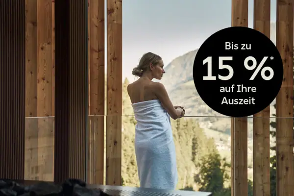 Eine Frau in ein Handtuch gehüllt schaut aus einem Fenster.