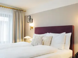 A cozy hotel room featuring a neatly made bed with plush pillows and a bedside lamp.