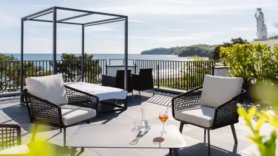 Patio mit Stühlen und einem Tisch auf einer Terrasse mit Meerblick.