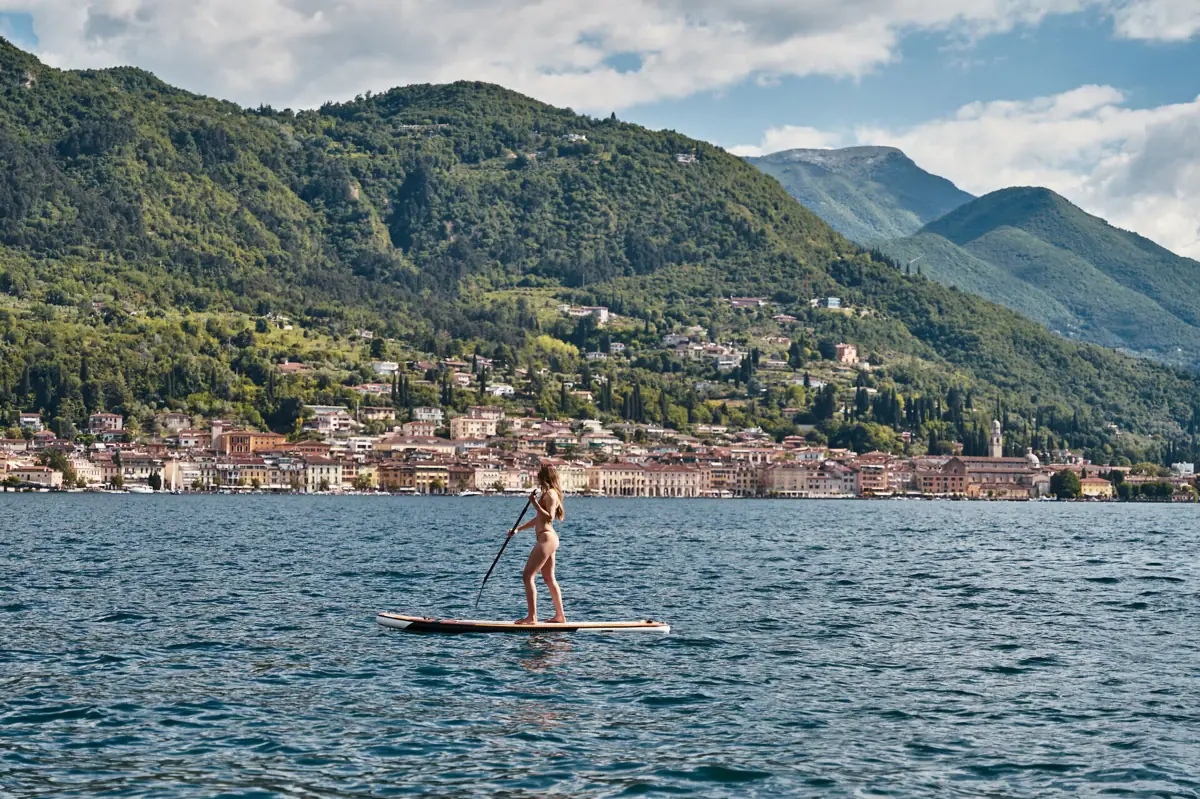 Eine Frau auf einem Paddleboard im Wasser mit einer Stadt im Hintergrund.